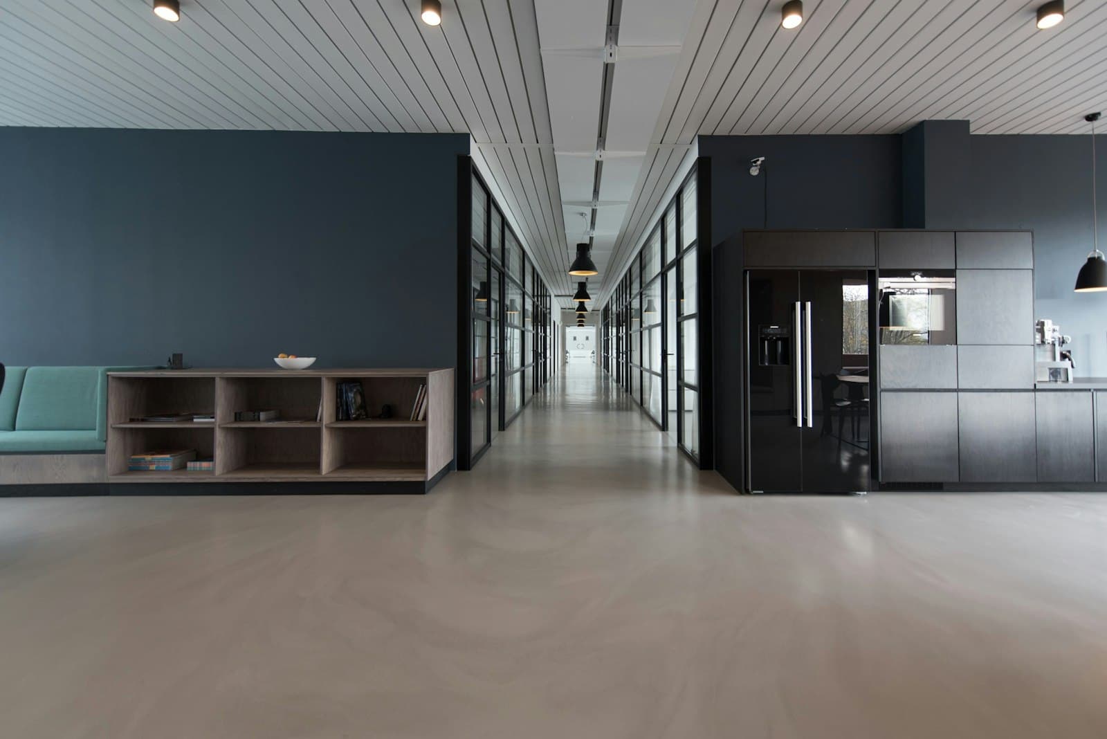 A modern open-plan office with a long glass corridor